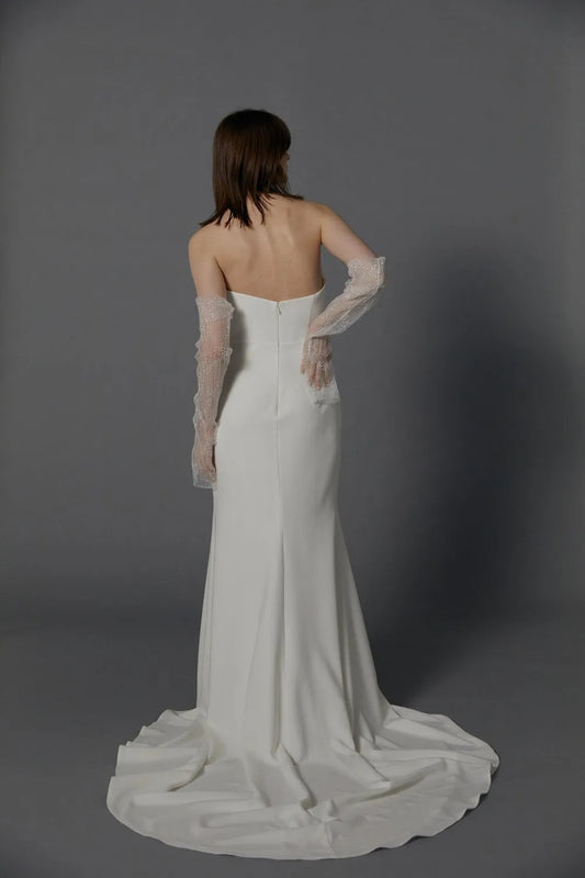 The unique strapless neckline creates a breathtaking statement of regal grandeur highlighting a modern high slit. A celebration of romance, luxury, and modernity.