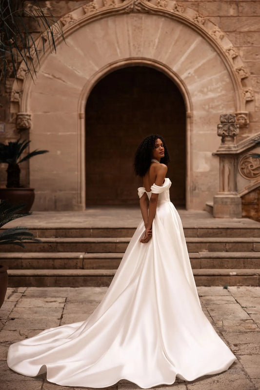 Introducing our captivating a-line wedding dress, a vision of elegance and sophistication. Crafted from lustrous glossy fabric, it radiates a subtle sheen, casting a mesmerizing glow as you glide down the aisle.