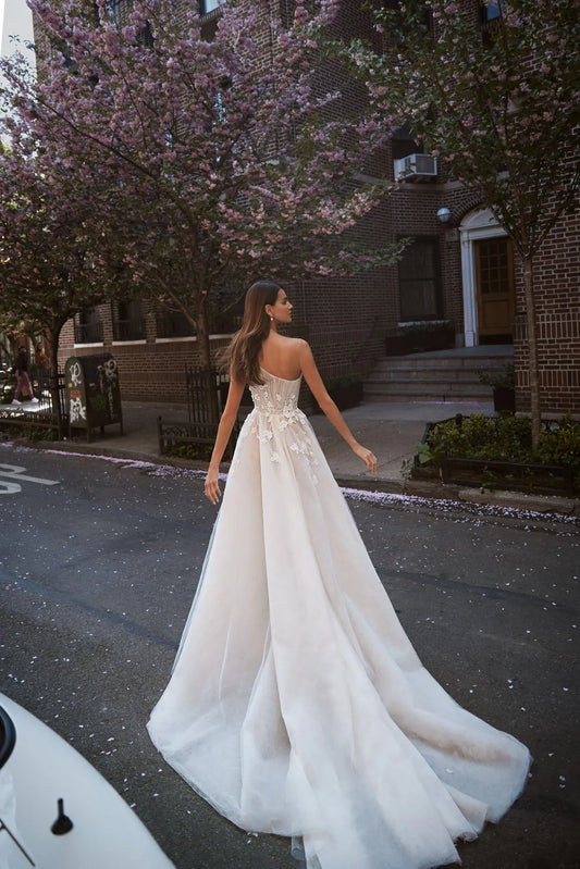 Expremely feminine and fragile wedding gown. The top is embellished with the scrunched up Tulle and floral elements that cover one shoulder. The skirt is made of numerous layers of Tulle with accentuated waistline and 3D floral lace.