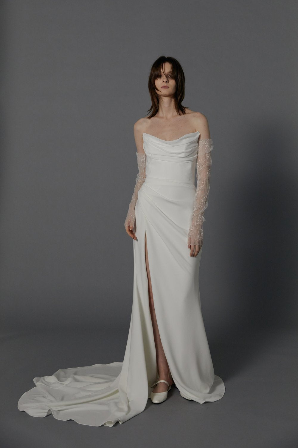 The unique strapless neckline creates a breathtaking statement of regal grandeur highlighting a modern high slit. A celebration of romance, luxury, and modernity.