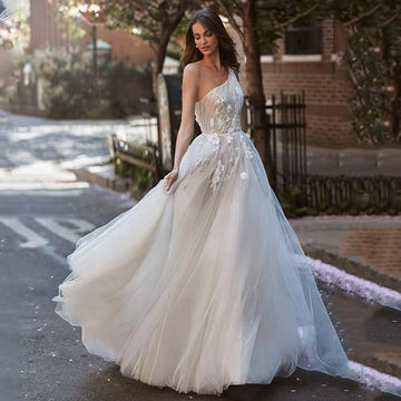 Expremely feminine and fragile wedding gown. The top is embellished with the scrunched up Tulle and floral elements that cover one shoulder. The skirt is made of numerous layers of Tulle with accentuated waistline and 3D floral lace.