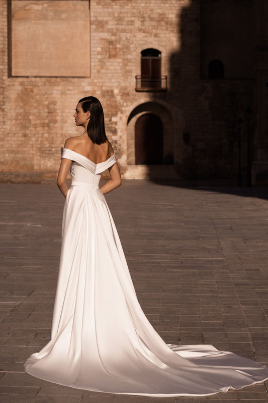 Introducing our stunning sheath wedding dress, an epitome of modern elegance and sophistication. Crafted from lustrous glossy fabric, it gracefully hugs your curves, exuding confidence and allure.